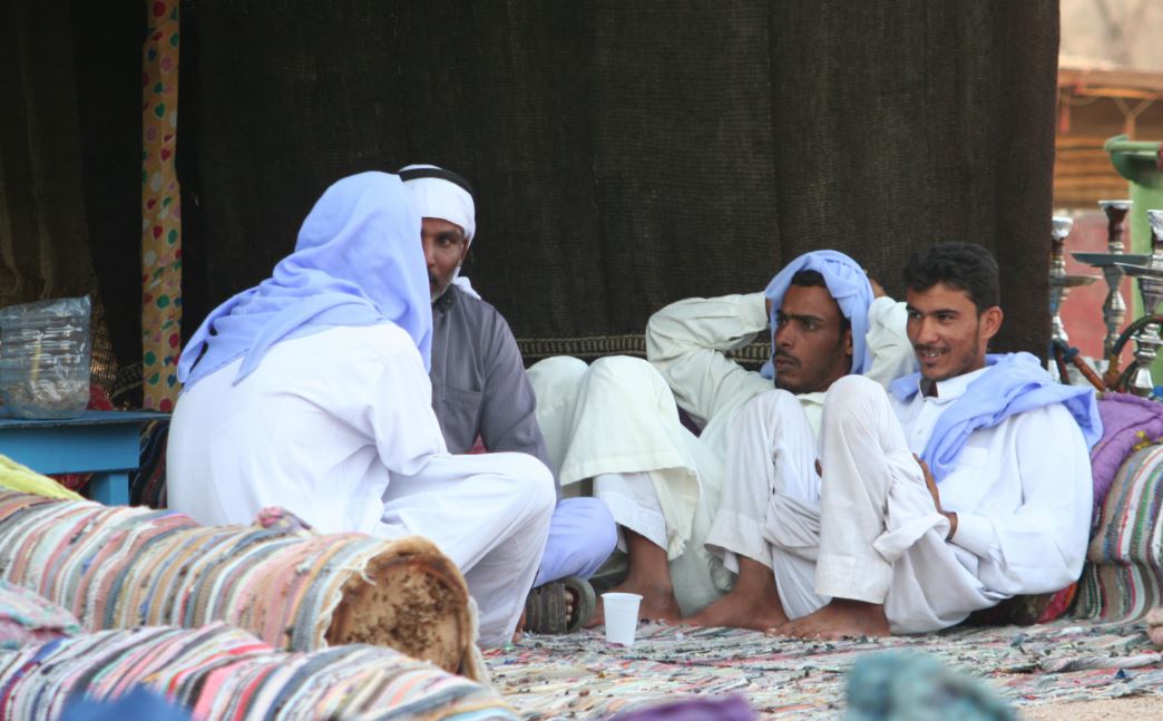 a picture of men sitting around talking and wearing attire typical of Arabs in the desert